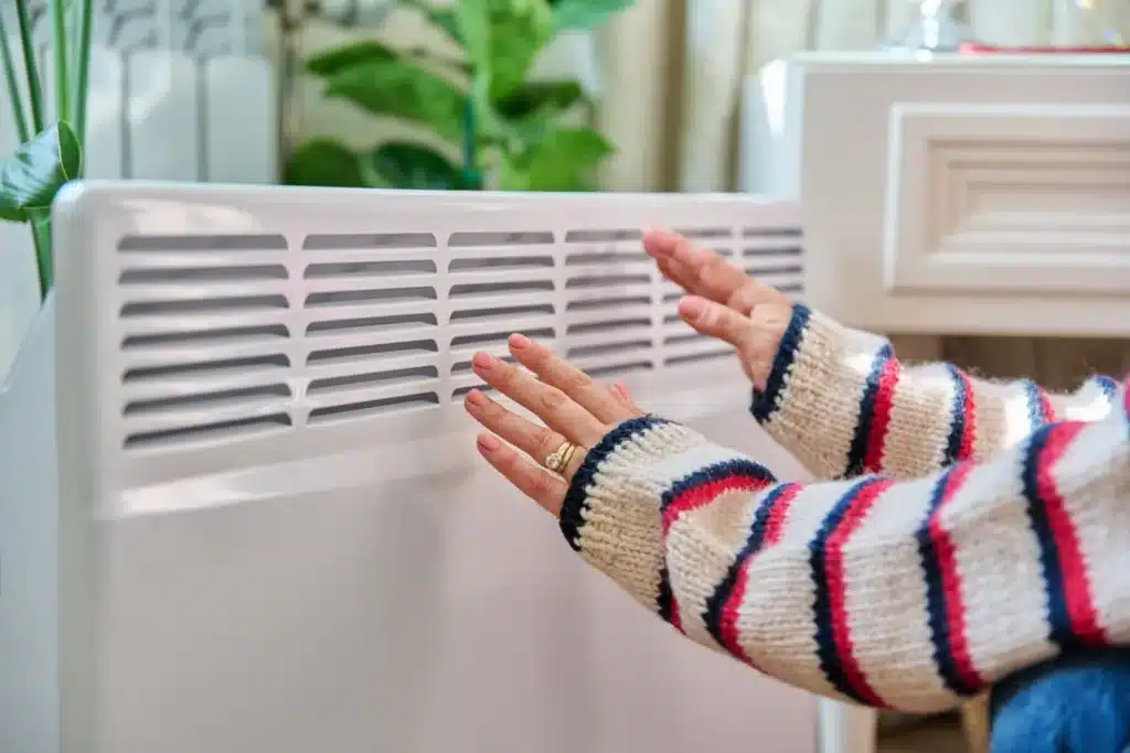 exemple d'un radiateur électrique avec une personne qui se réchauffe les mains