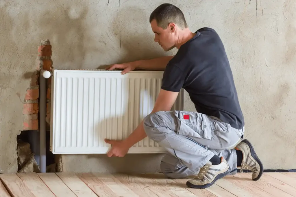 technicien rge en train d'installer un radiateur a inertie